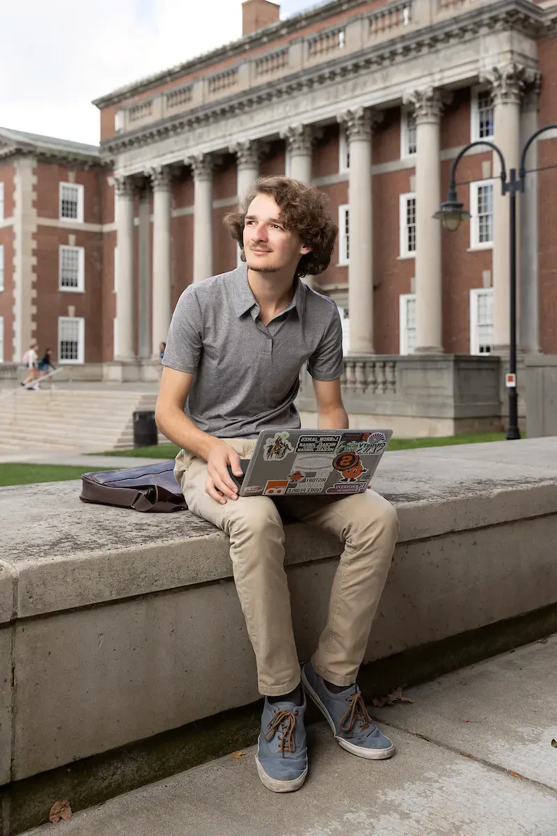 Dominic Chiappone working on computer outside of the Maxwell School of Citizenship and Public Affairs.